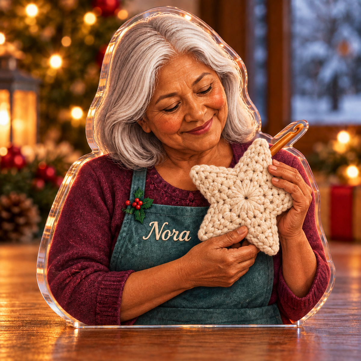 Front-view digital preview of a Christmas crochet star pride acrylic plaque with example name Nora integrated into the the illustrated front apron name stitching