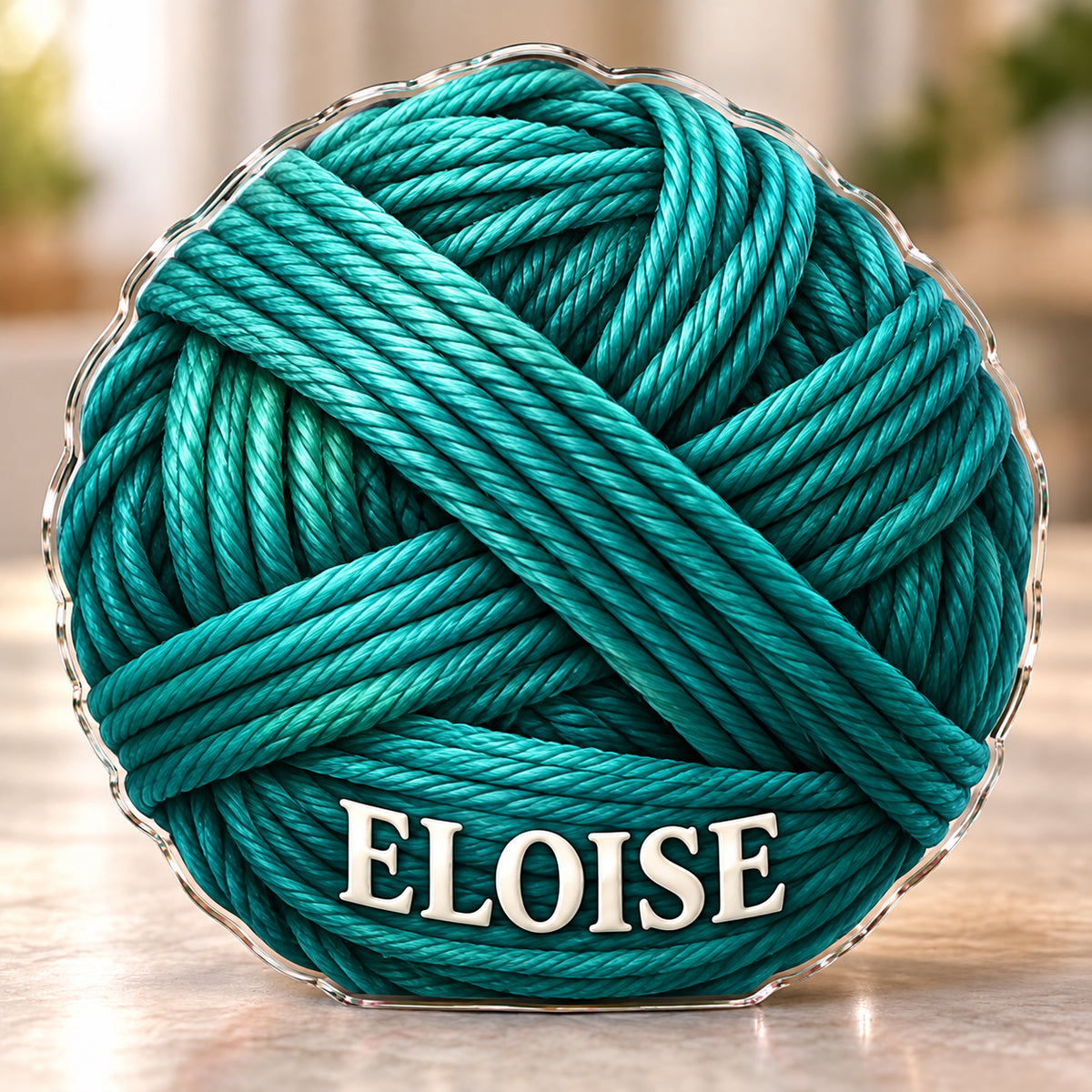 Front-view digital preview of a teal yarn ball subject-shaped acrylic plaque with ELOISE printed on its lowest intrinsic illustrated yarn band