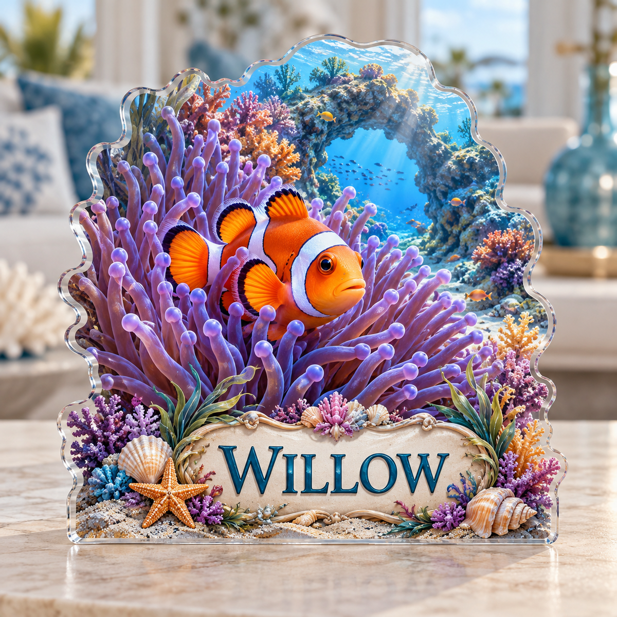Front view of a anemone clownfish reef custom-shape acrylic plaque with example name WILLOW, displayed in a softly blurred ocean-inspired living room on pale stone console