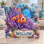 Front view of a anemone clownfish reef custom-shape acrylic plaque with example name WILLOW, displayed in a softly blurred ocean-inspired living room on pale stone console