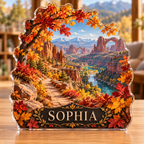 Front view of a autumn canyon trail custom-shape acrylic plaque with example name SOPHIA, displayed in a softly blurred warm outdoor-inspired reading room on a light wood tabletop