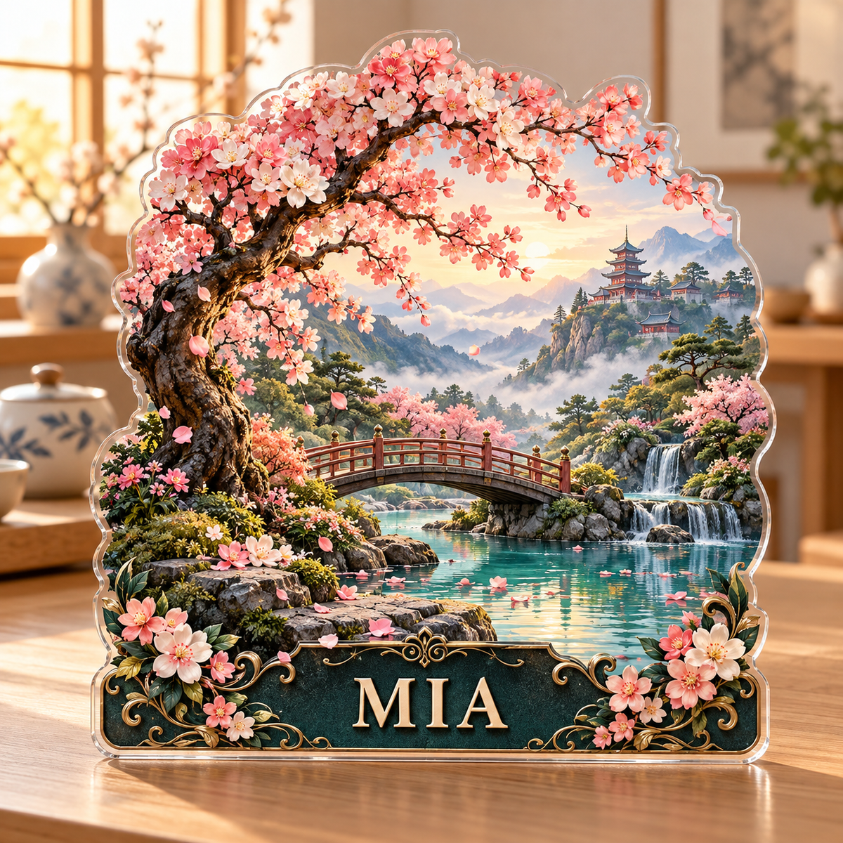 Front view of a cherry blossom pagoda custom-shape acrylic plaque with example name MIA, displayed in a softly blurred serene tea room with warm dawn window light on pale wooden console