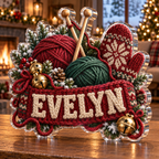 Front view of personalized christmas knitting cottage acrylic plaque with sample name EVELYN, displayed in a softly blurred Christmas knitting cottage